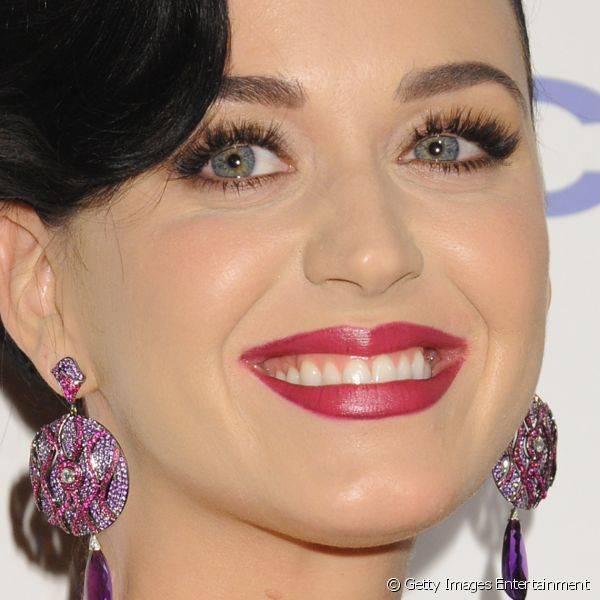 A cantora Katy Perry usou um batom vermelho com o fundo rosado em um efeito cremoso, combinado com a sombra dourada e cílios postiços